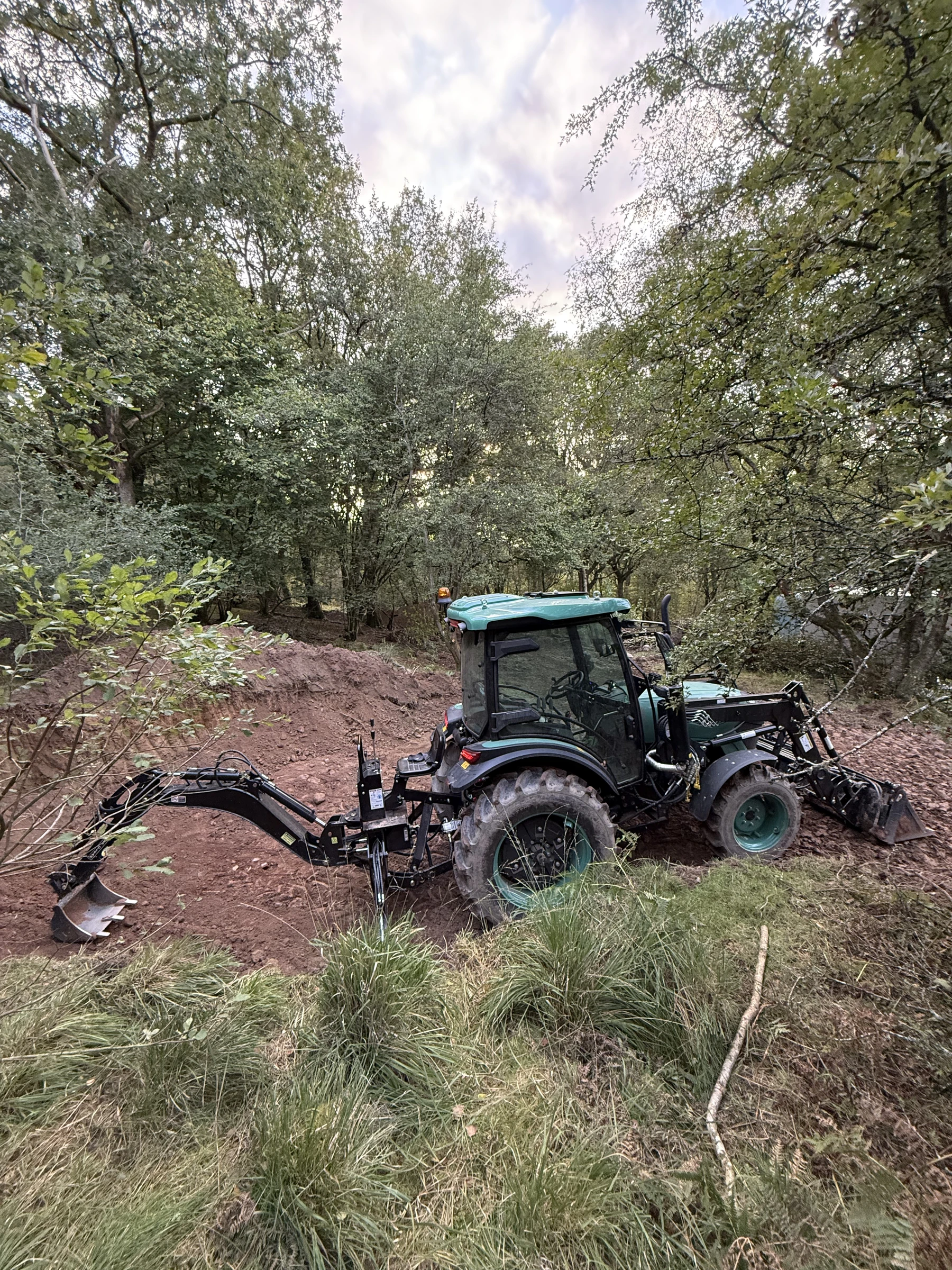 Our BULL with its HW Series 10 backhoe and HW Series 10 loader working in the woodland
